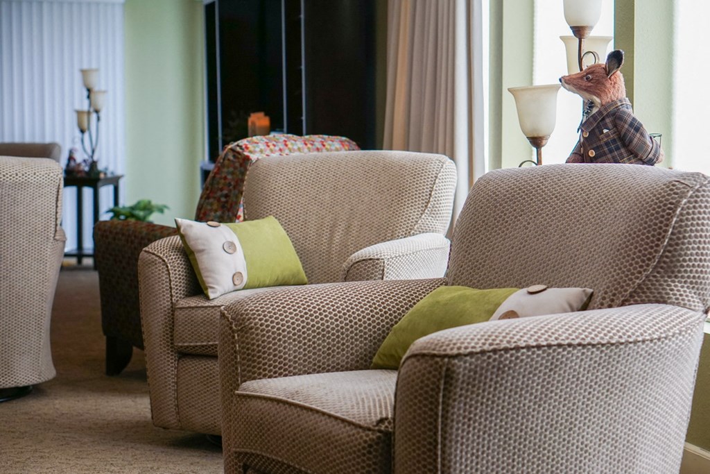 a living room filled with furniture and a stuffed animal on a chair