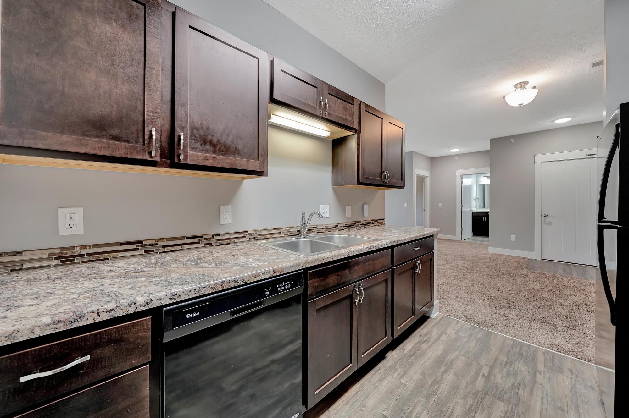 A kitchen with dark brown cabinets and a granite countertop.