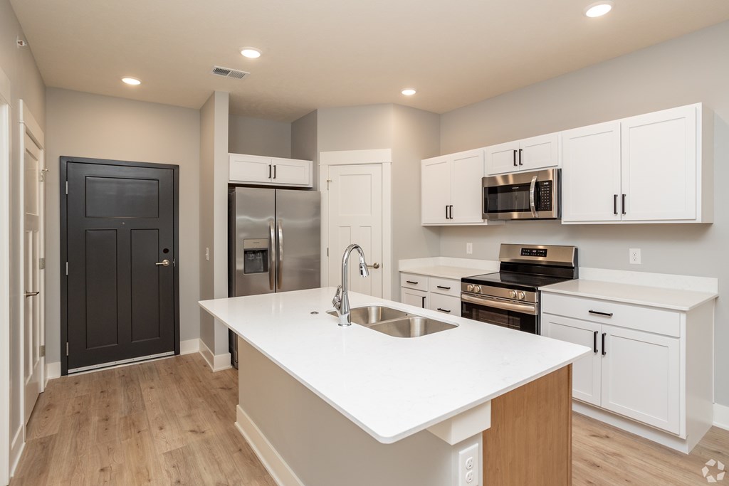 A modern kitchen with white countertops and stainless steel appliances.
