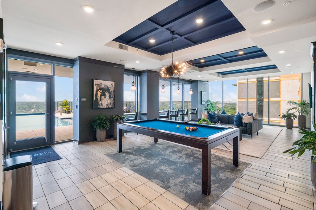 a pool table in the lobby of a building with windows
