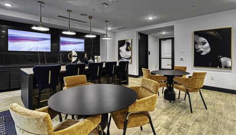 a dining area with tables and chairs and a kitchen with a projector screen