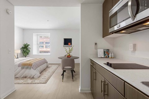 A modern kitchen with a bedroom in the background.