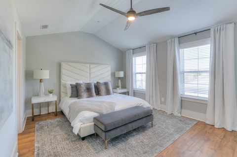 A bedroom with a large bed and a ceiling fan.
