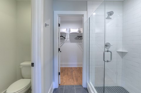 A white bathroom with a toilet and a walk in shower.