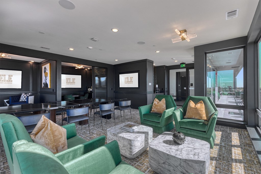 a lounge area with green chairs and tables and a large window