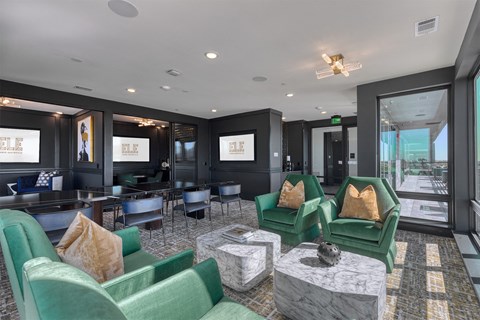 a lounge area with green chairs and tables and a large window