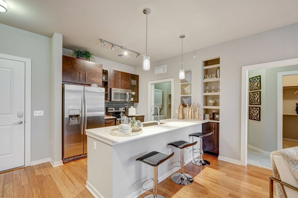 Kitchen with island, white quartz counters and dark cabinets at ALARA Union Station Apartment Homes, Denver, 80202
