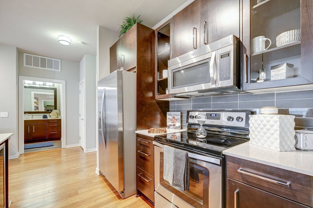 Kitchen with wooden cabinets and stainless steel appliances at ALARA Union Station Apartment Homes, Denver, 80202