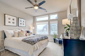 a bedroom with a large window and a ceiling fan