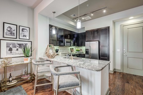 a kitchen with a marble counter top and a bar with chairs