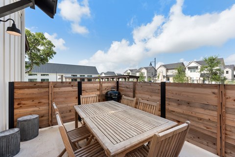 a patio with a wooden table and chairs and a wooden fence