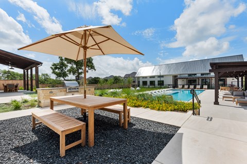 a patio with tables and an umbrella next to a pool