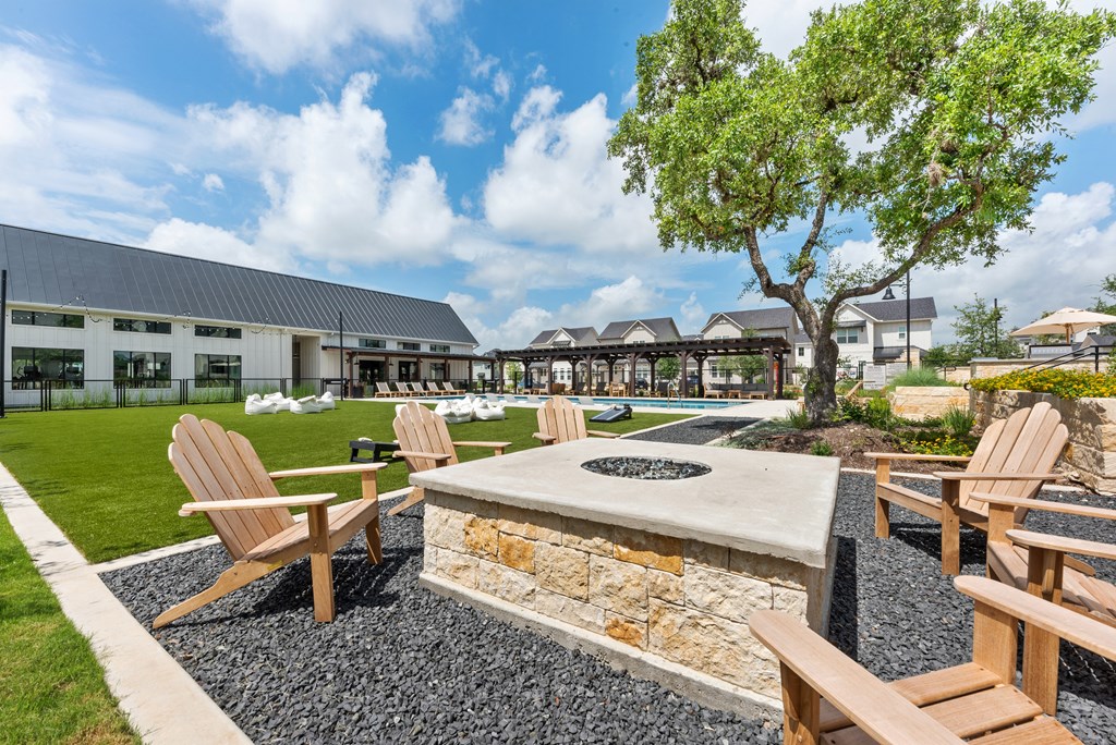 a fire pit with chairs and a tree in front of a building
