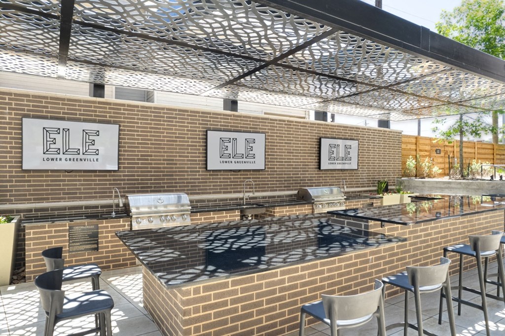 a large outdoor kitchen with brick walls and stainless steel appliances