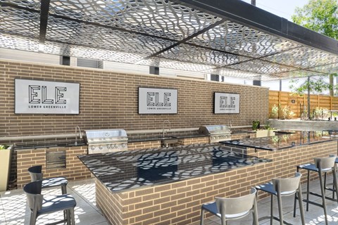 a large outdoor kitchen with brick walls and stainless steel appliances