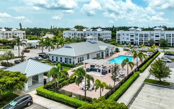 A large white building with a pool in front of it.