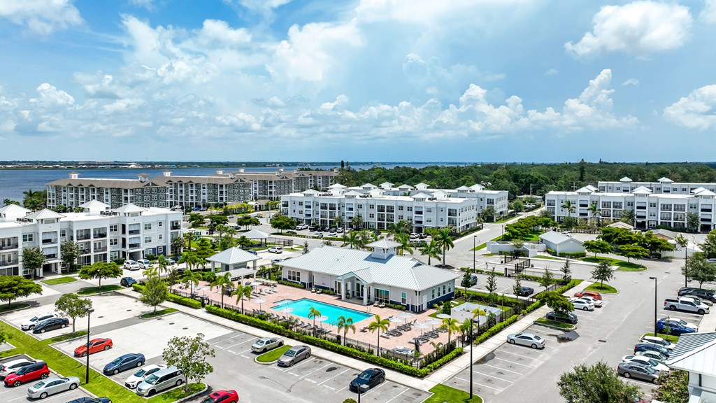 A large white resort with a pool and a parking lot.