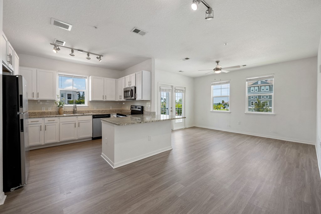 A spacious kitchen with white cabinets and a black refrigerator.