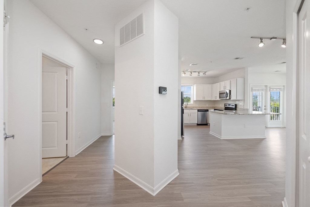 A spacious, empty room with light wood flooring and white walls.