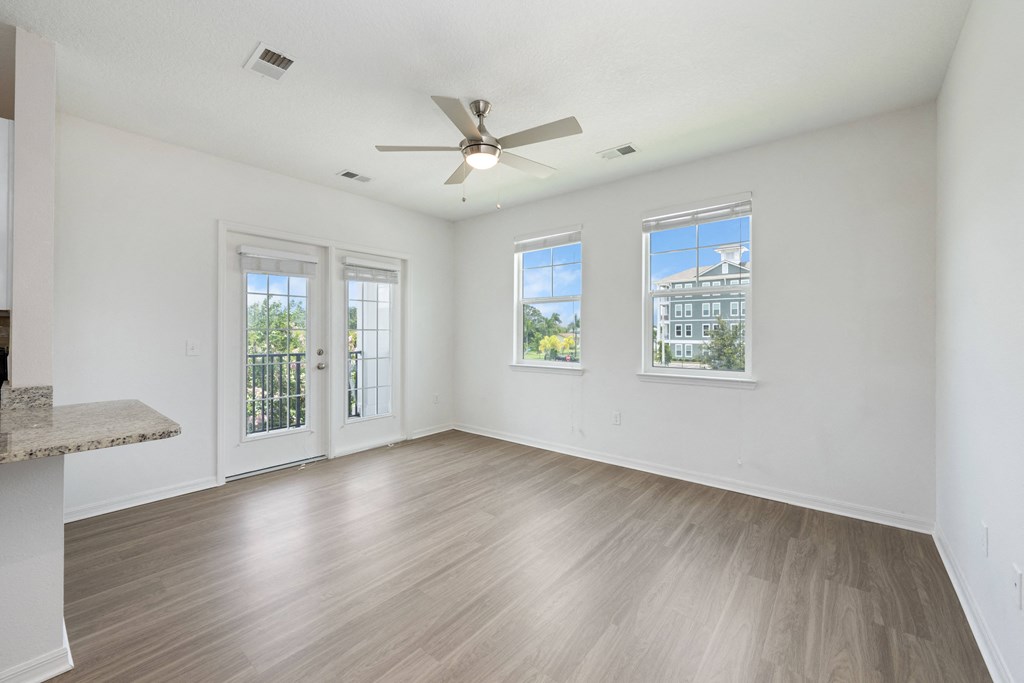 A room with a ceiling fan and three windows.