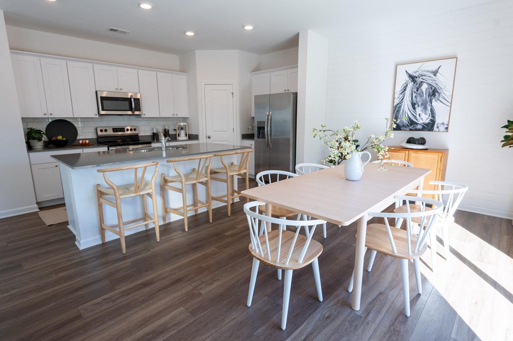 a dining room and kitchen with a wooden table and chairs