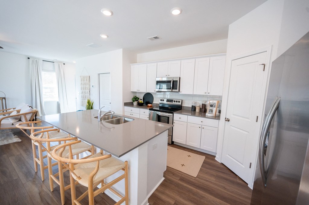 a kitchen with white cabinets and stainless steel appliances and a gray counter top