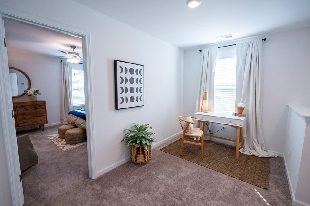 an open living room and bedroom with a desk and a mirror