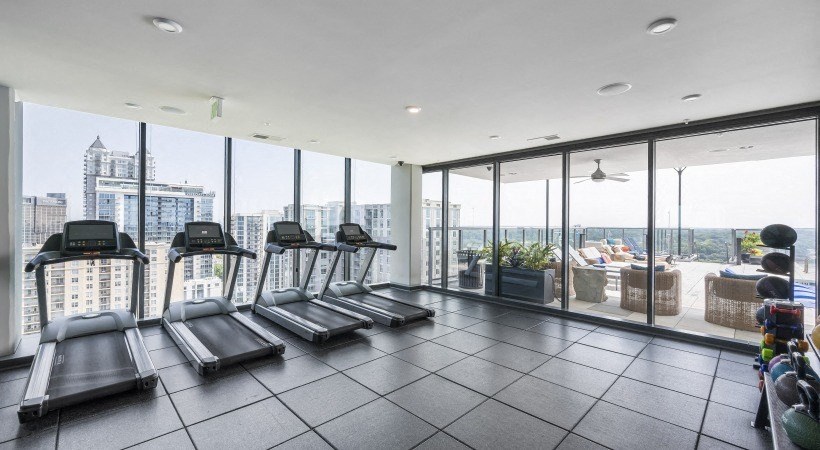 a gym with cardio equipment and a view of the city