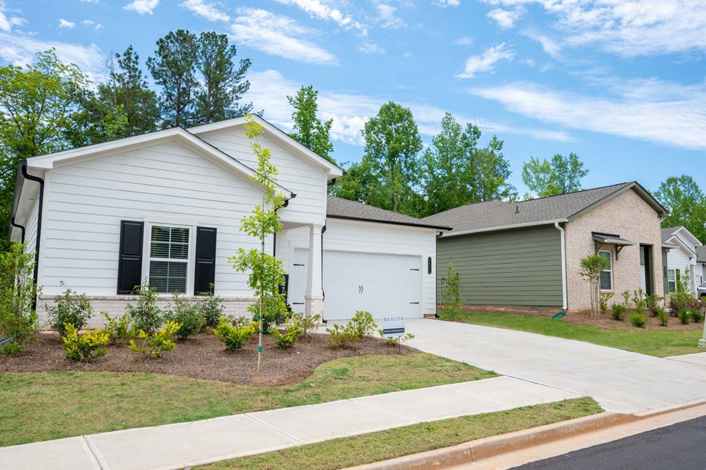 a white house with black shutters and a green garage door