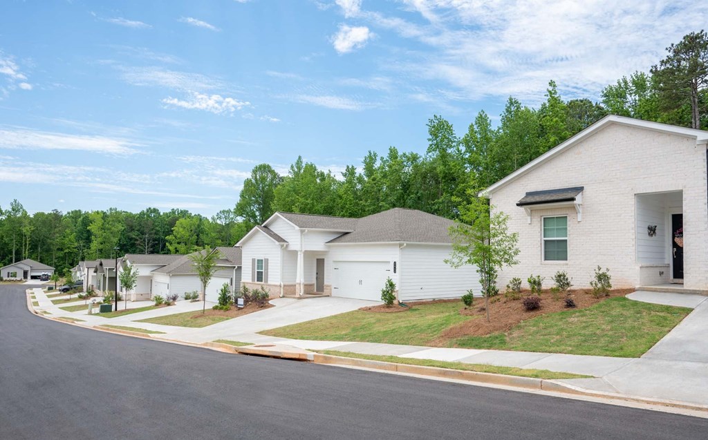 a street view of a subdivision with white houses and trees in the background