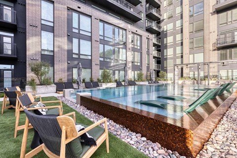 an apartment with a pool and chairs in front of a building
