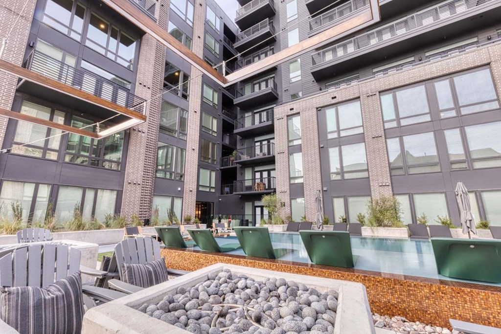 an outdoor patio with a fire pit in front of an apartment building
