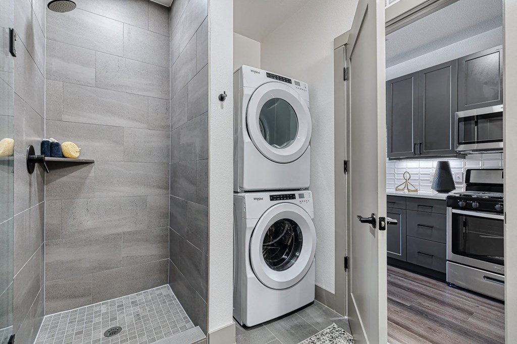 a washer and dryer in a laundry room with a shower and a sink