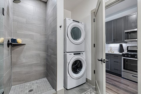 a washer and dryer in a laundry room with a shower and a sink