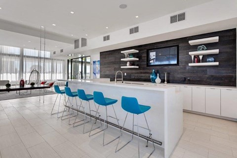 a large white kitchen with blue chairs in front of a bar