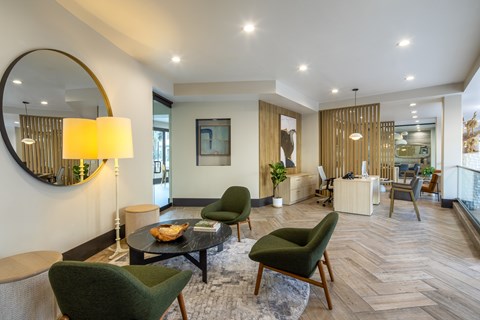 A modern living room with a green chair and a round mirror on the wall.