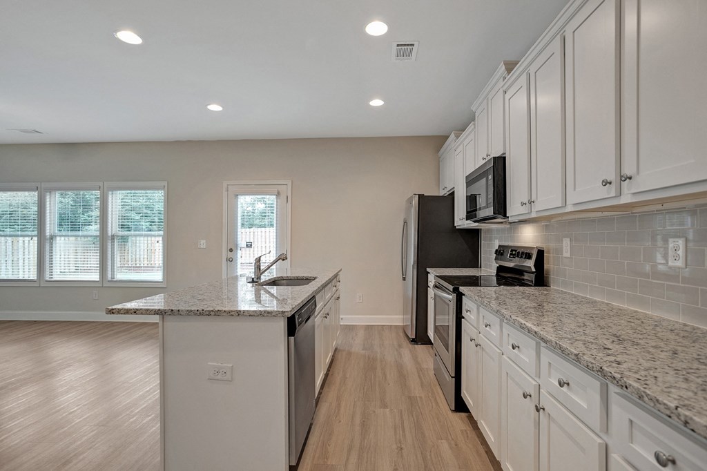 an empty kitchen with granite counter tops and white cabinets