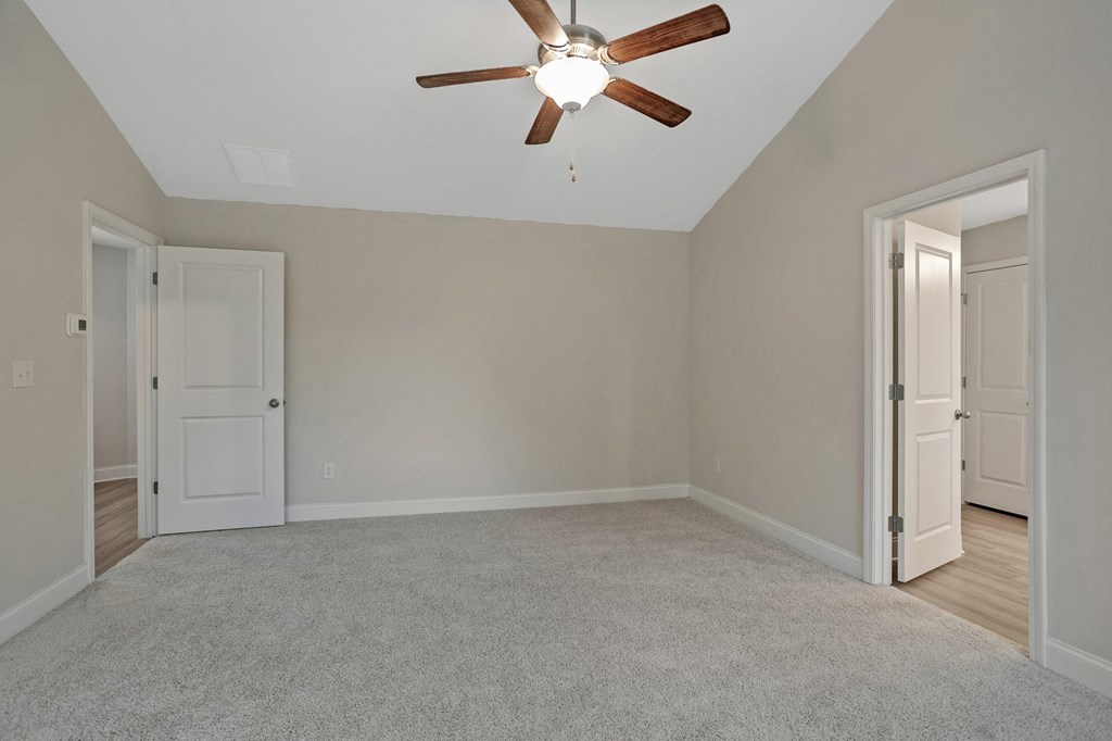 an empty living room with a ceiling fan and white doors