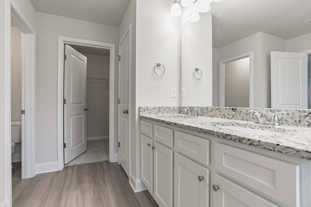 a bathroom with white cabinets and marble counter tops