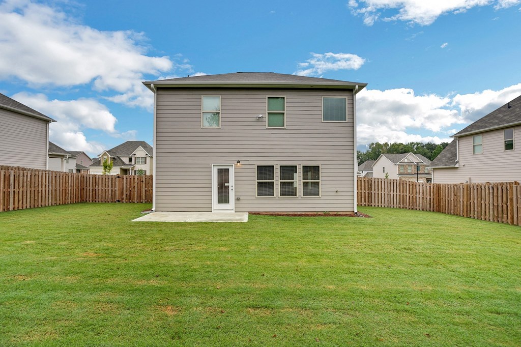 a small house in a fenced in backyard with a green lawn