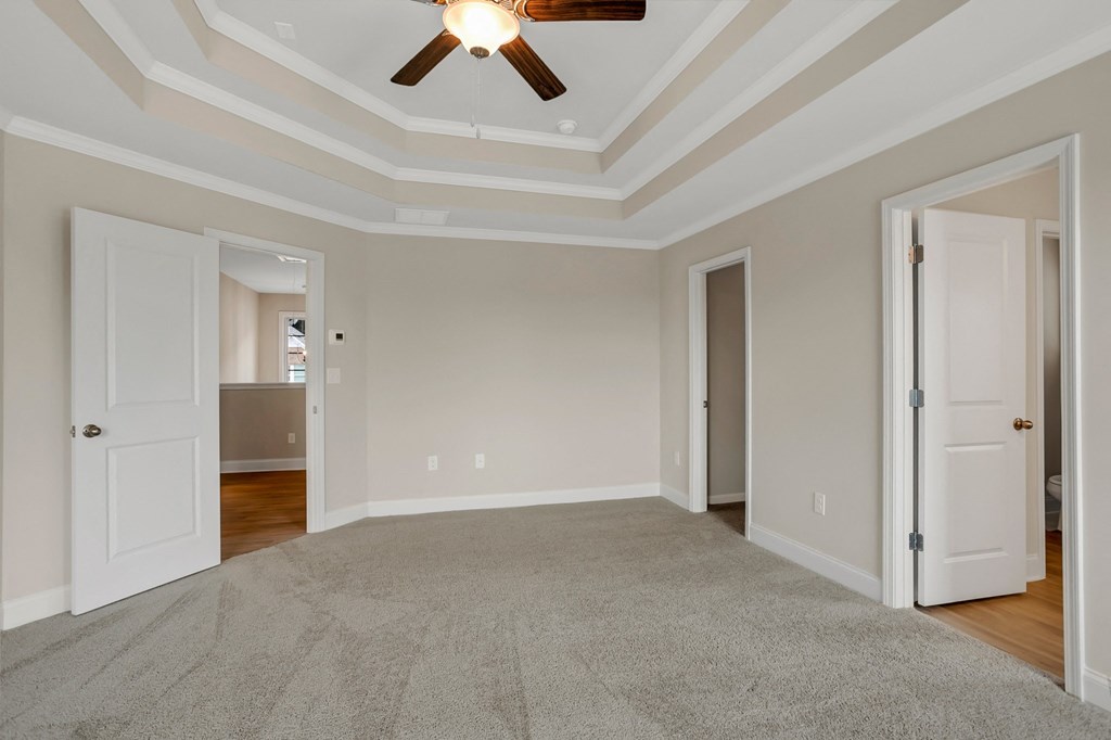 an empty living room with a ceiling fan and doors