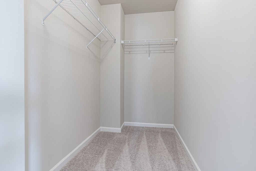 an empty closet with a white wall and a hanging rack on the wall