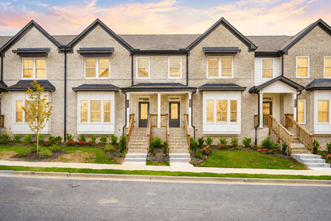 A row of houses with front yards and steps leading to the doors.