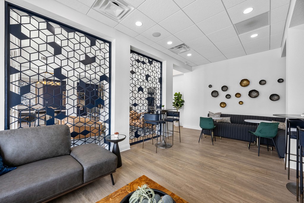 A grey sofa is in front of a geometric wall mural in a modern living room.