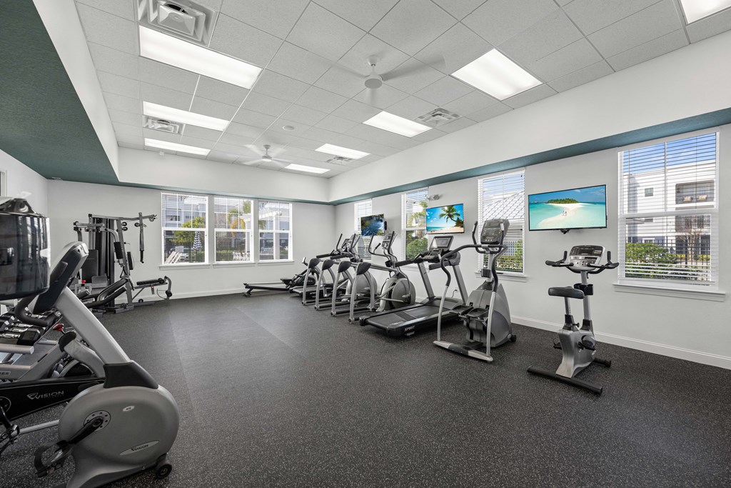 A gym with a variety of exercise equipment including treadmills, stationary bikes, and elliptical machines.