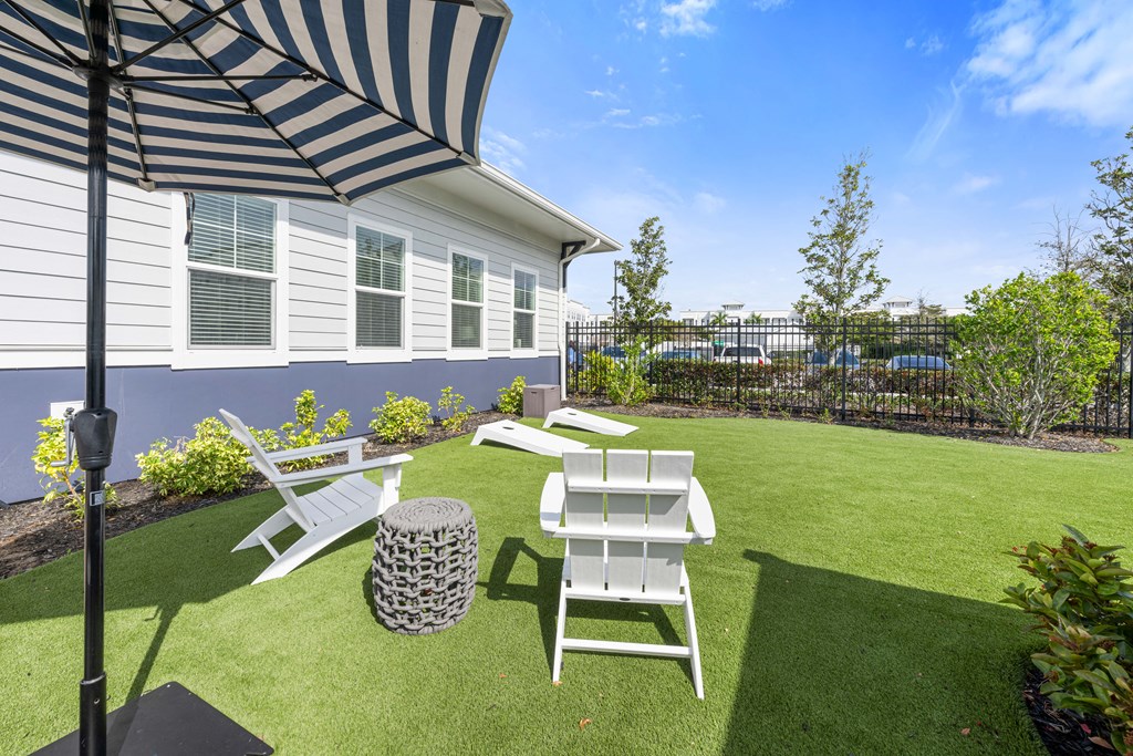 A patio with a striped umbrella and two chairs.