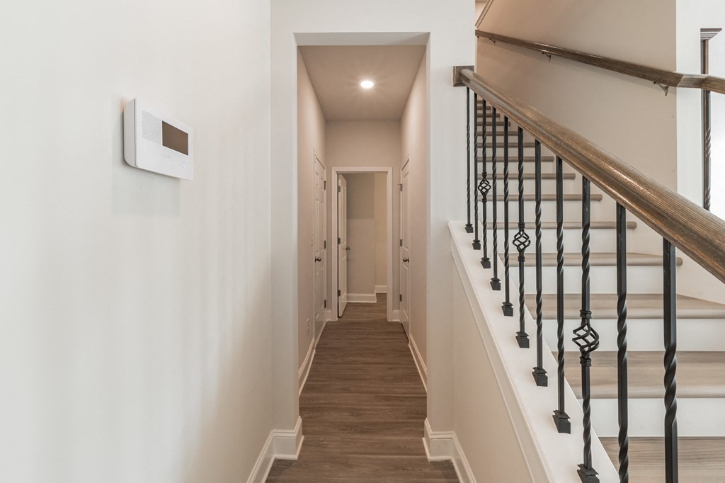 a hallway with white walls and a staircase with a railing and a white door
