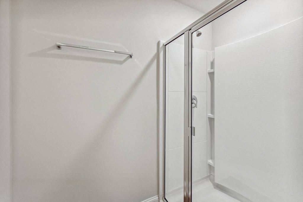 a walk in shower in a bathroom with a sliding glass door