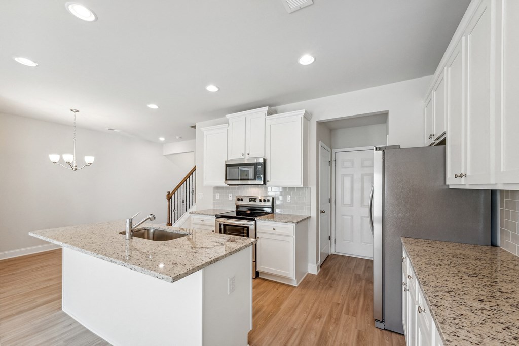 an open kitchen with granite counter tops and white cabinets