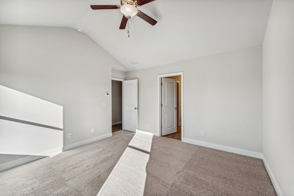 a spacious living room with white walls and a ceiling fan